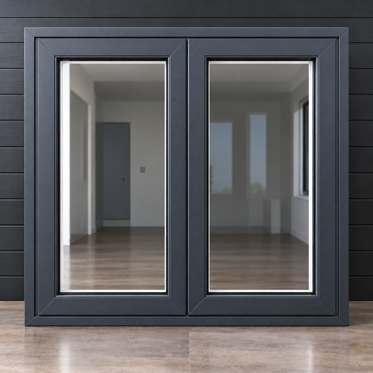 A modern double-pane sliding glass door or window frame in matte black, shown standing upright against a dark paneled wall with a light wood floor visible through the glass.